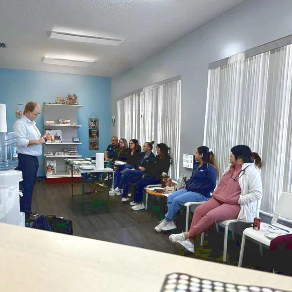 Staff training in the light and airy waiting room, with full-length windows on one side. A selection of products available to purchase are showcased at one end of the room.
